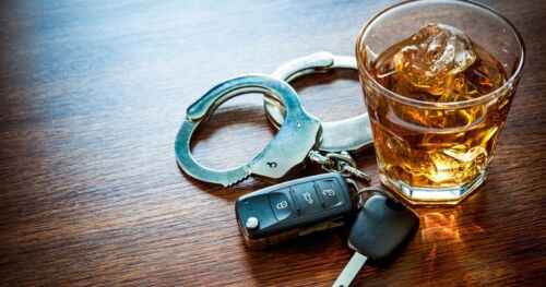 A glass of alcohol with keys and handcuffs next to it