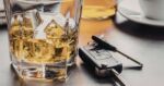 Car keys sitting next to a glass of whiskey
